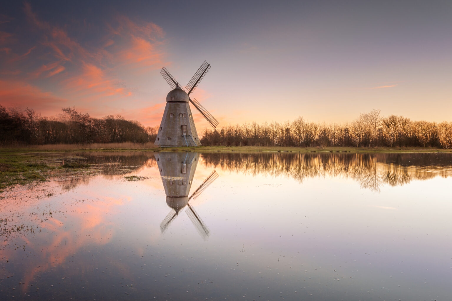 Windmühle spiegelt sich im See bei Sonnenuntergang