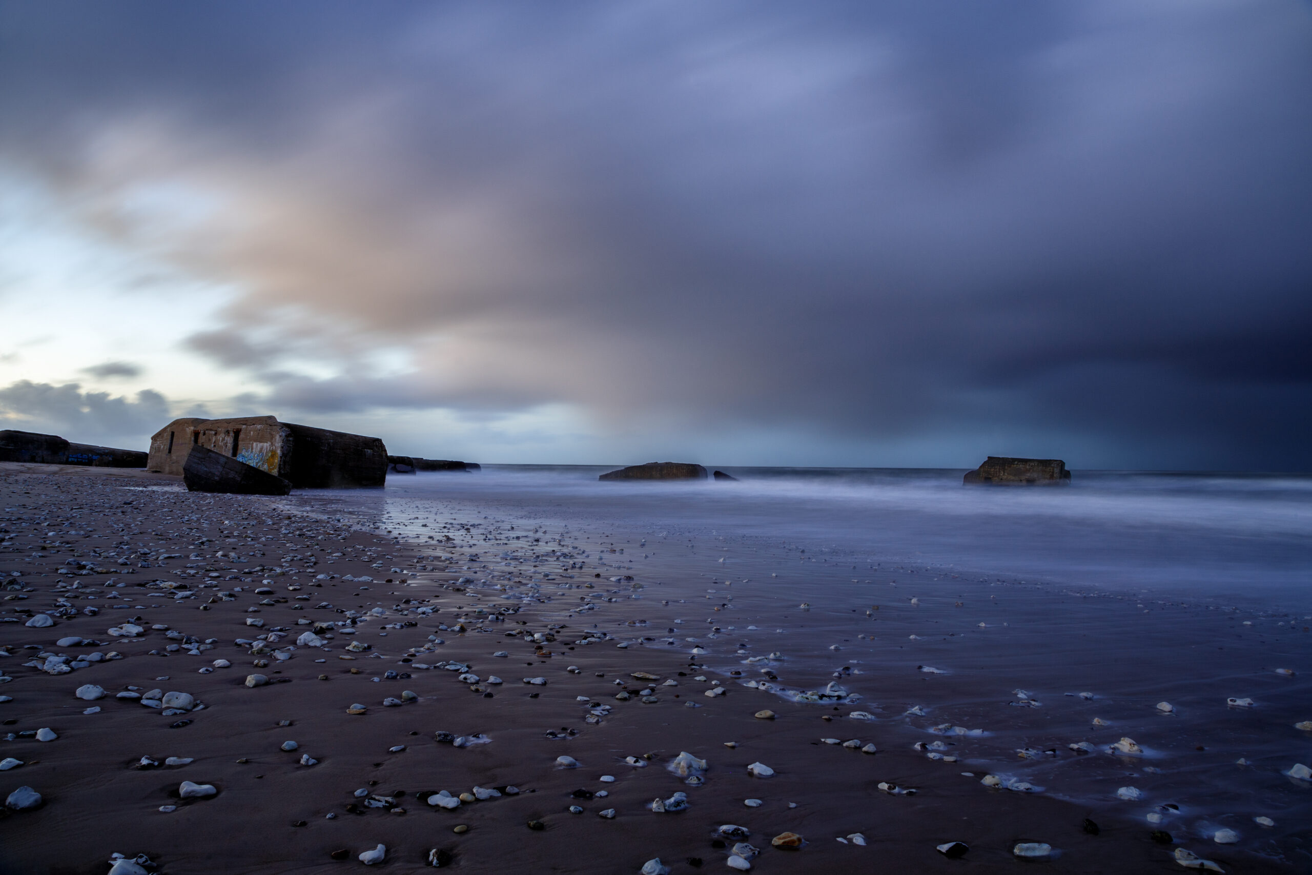 Portfolio Sturmwolken über einem Steinstrand an der Küste