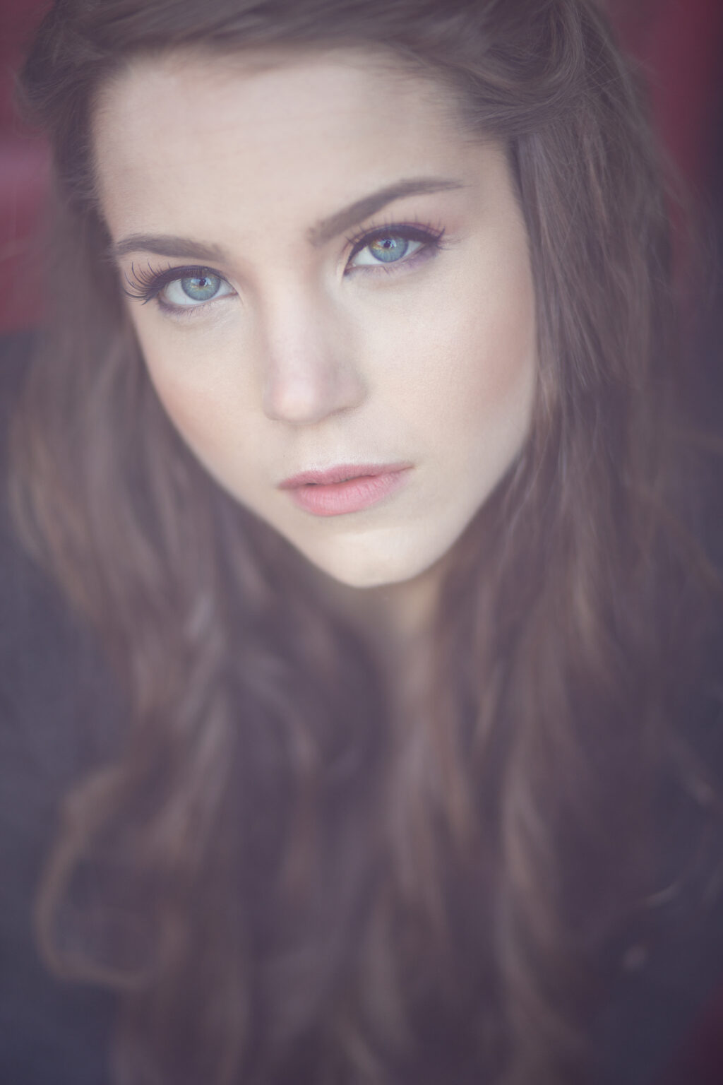 Nahaufnahme einer jungen Frau mit langen Haaren und direktem Blick