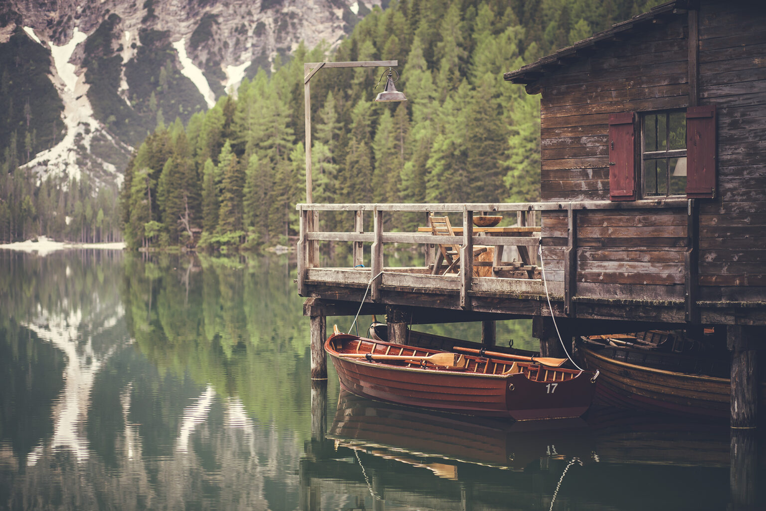 Holzbootshaus mit roten Ruderbooten am Bergsee