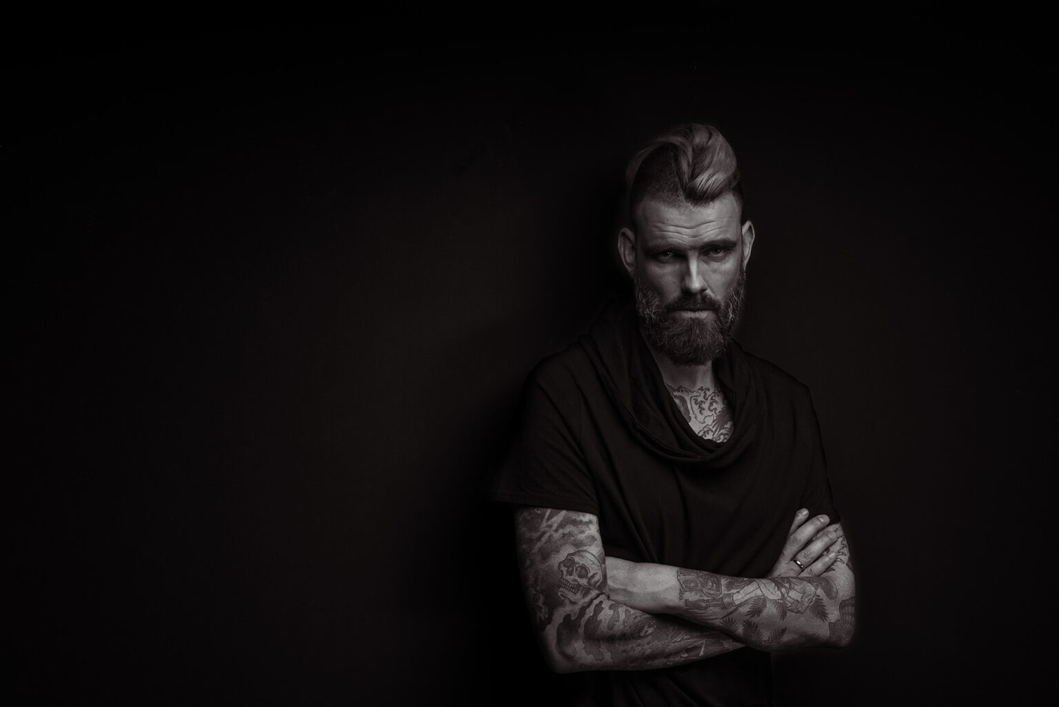 Portrait eines Mannes mit verschränkten Armen im Low-Key-Licht